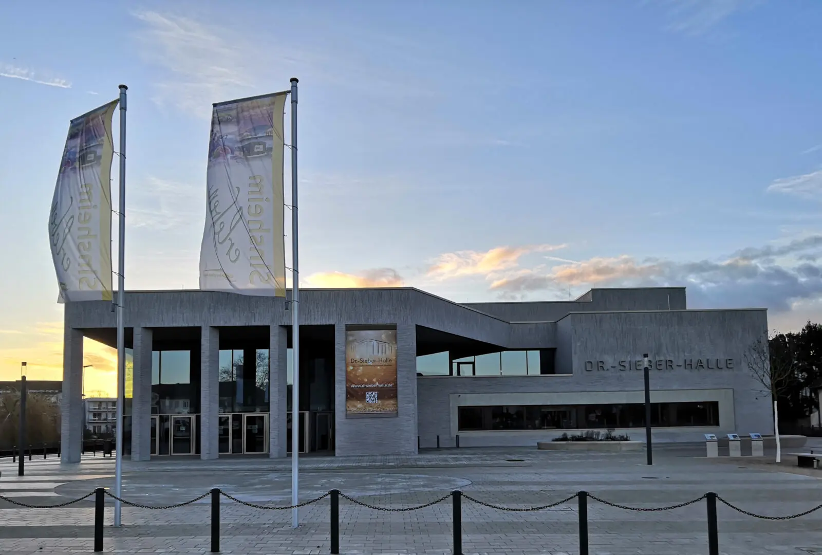 Dr.-Sieber-Halle der Stadt Sinsheim von vorne inklusive Vorplatz und Fahnen.